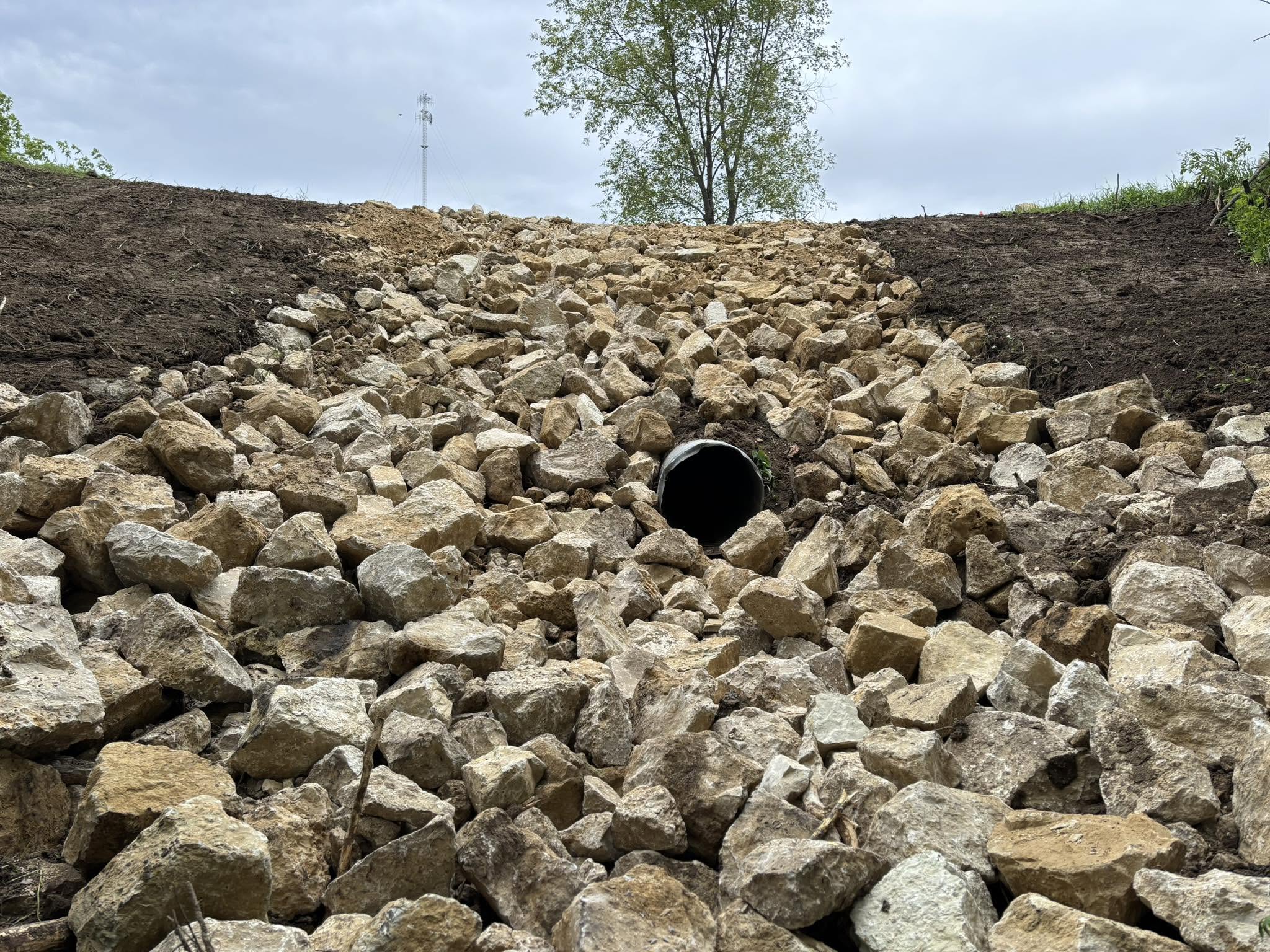 Culvert opening surrounded by riprap in a graded drainage channel
